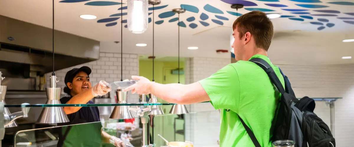 Student being served a meal by employee