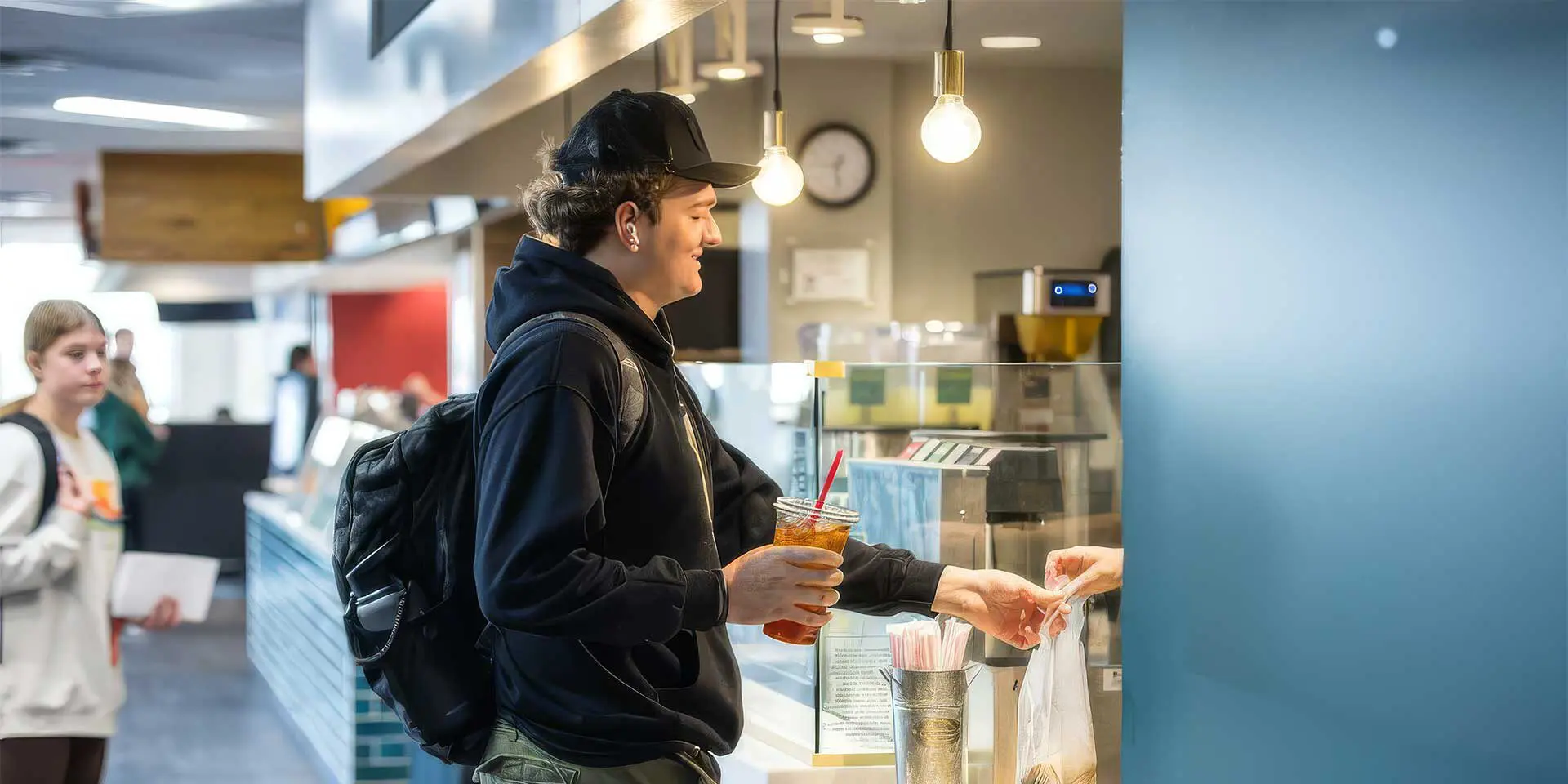 Student smiling while being handed bag of food from counter